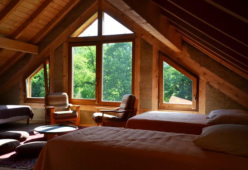 Couchage sous rampants, fenêtre triangulaire ouverte sur les arbres